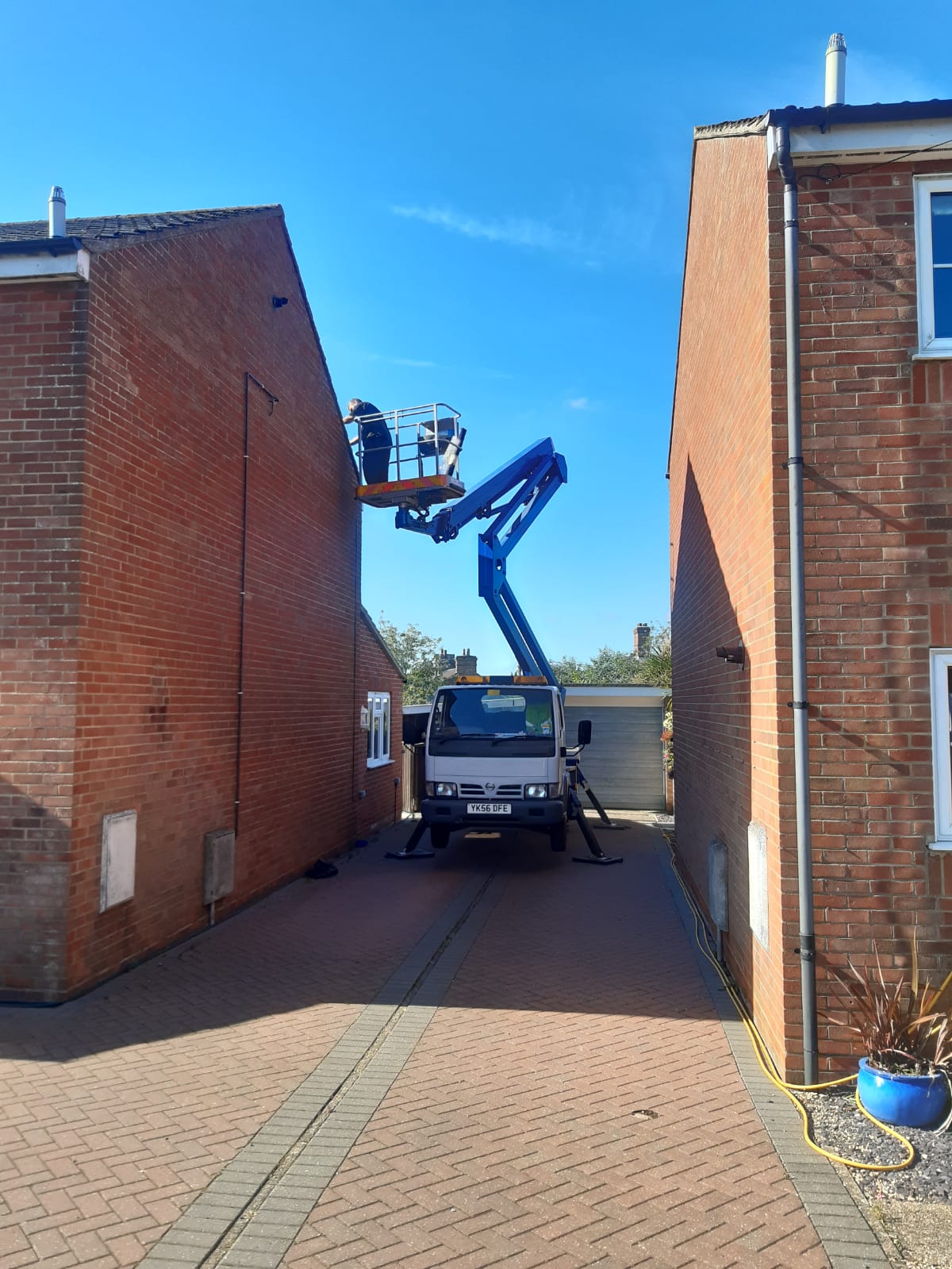 Pest control operative working from an access platform between two houses in Suffolk